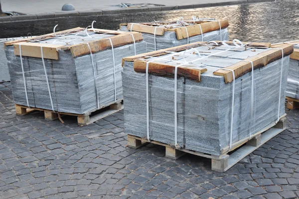 Stacks of various. Building and construction materials, stone and concrete pavers (paving stone) or patio blocks organized on pallets.