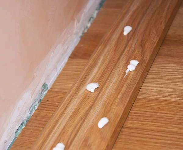 Close up on Oak Wood Parquet Installation.Caulking silicone from