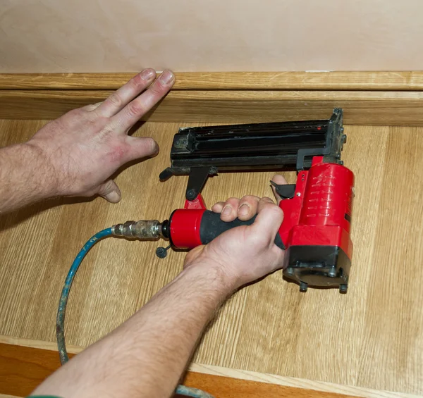 Worker pound in a nail to batten for wooden oak floor, floating
