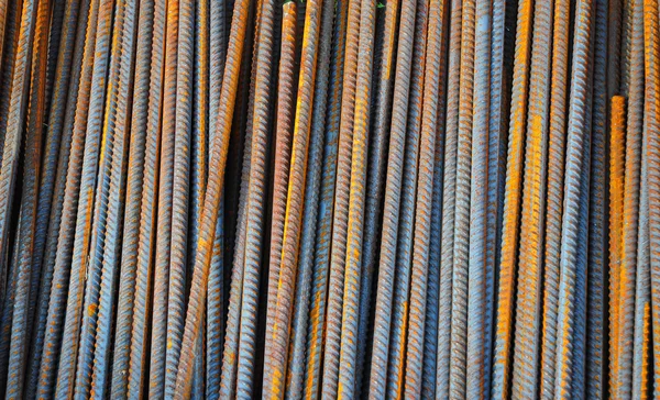 Reinforcing bar, or rebar, is a common steel bar that is hot rolled and is used widely in the construction industry, especially for concrete. Steel Rebar Textured Background.