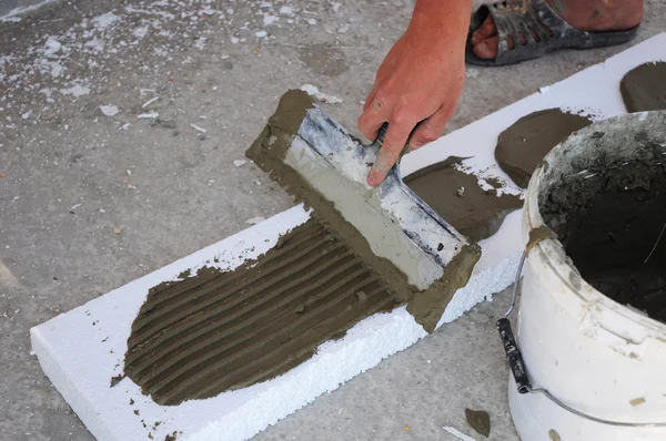Man\'s Hand Plastering a Wall Styrofoam or Foam Board Insulation with Trowel.