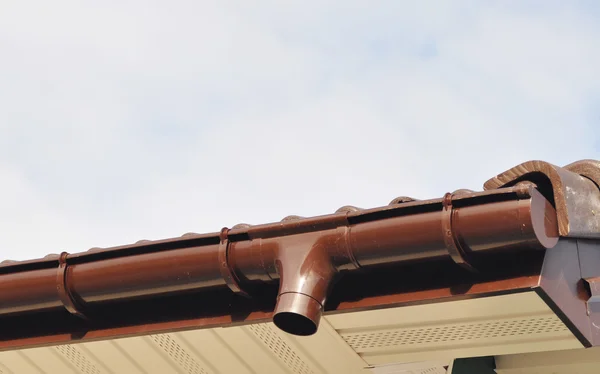 New Rain Gutter Drain Pipe Downspout Installation on the Unfinished House Facade Wall Outdoor