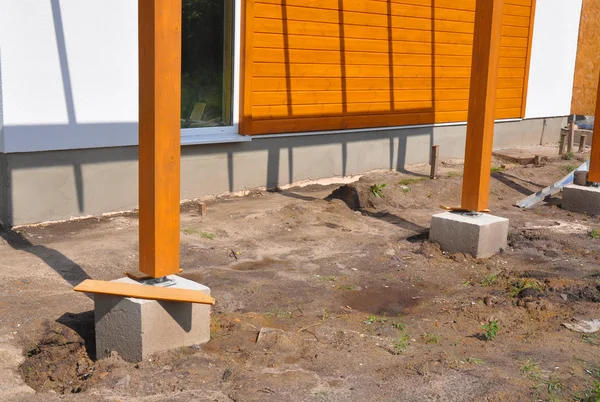 Wooden pillar on the construction site with screw and place for terrace.