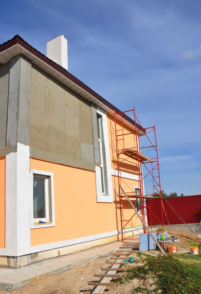 Close up on painting house wall. Construction or repair of the rural house with, eaves, windows, chimney, fixing facade, insulation, plastering and painting outdoor. House facade construction