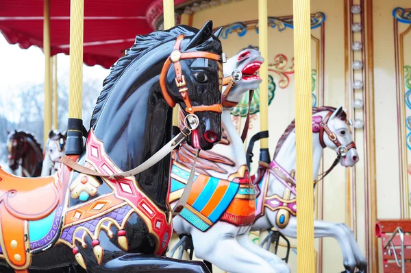 Beautiful horse carousel in a holiday park. Three horses on a traditional fairground vintage carousel. Merry-go-round with horses.