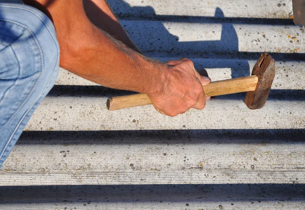 How to pull out the nails correctly from asbestos old roof tiles. Roof worker repair dangerous asbestos old roof tiles. Roofing construction.