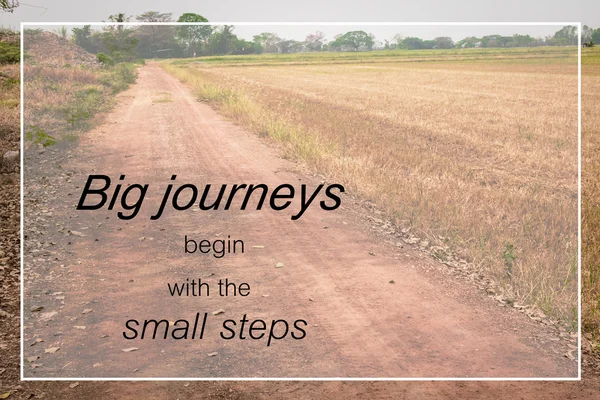 Word  Big journeys begin with the small steps.Inspirational motivational quote on a countryside road background