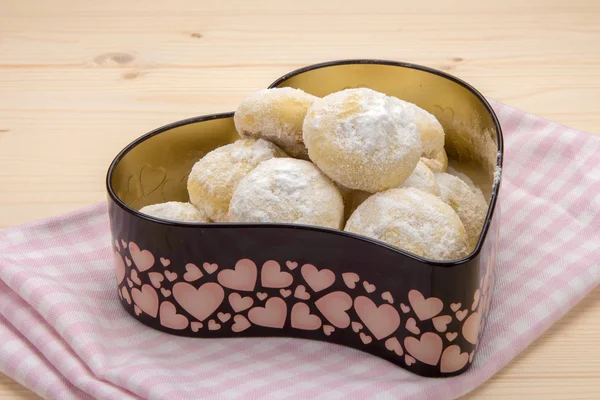 Small cookies in powdered sugar in a tin box on cotton checkered napkin