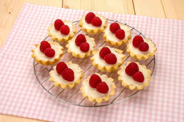 Homemade small cakes with cream cheese and fresh raspberries on
