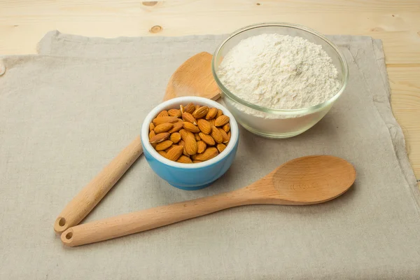 A blue ceramic bowl with almonds, a glass bowl with flour