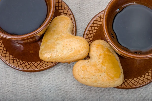 Two homemade cookies in shape of hearts, coffee