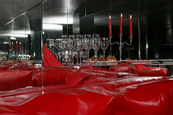Glasses and candles in red interior with mirrors