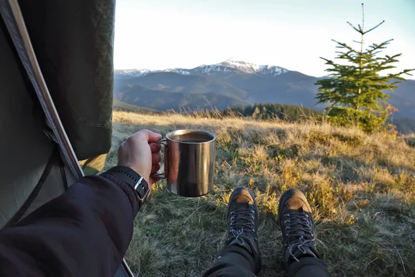 Tourist with a cup of coffee in tent with mountain view