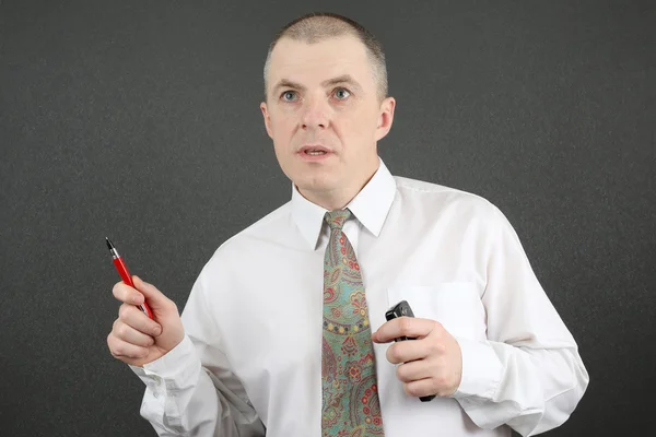 Business man in white shirt shows a red pen to the side