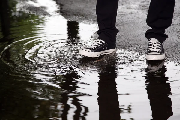 Man stops with his foot in a puddle