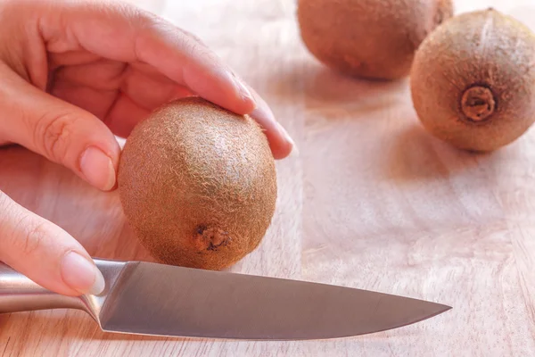 Woman food preparation - cutting a kiwi fruit.