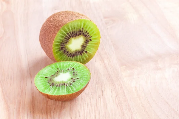 Kiwi fruit cut into pieces on a wooden background.