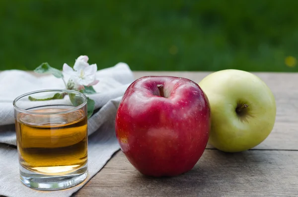 Apple juice and apples (red and green) on a wooden table