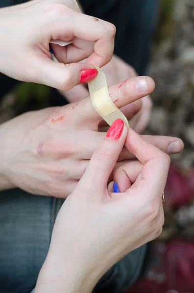 First aid for a cut finger, applying sticking plaster on a finger.