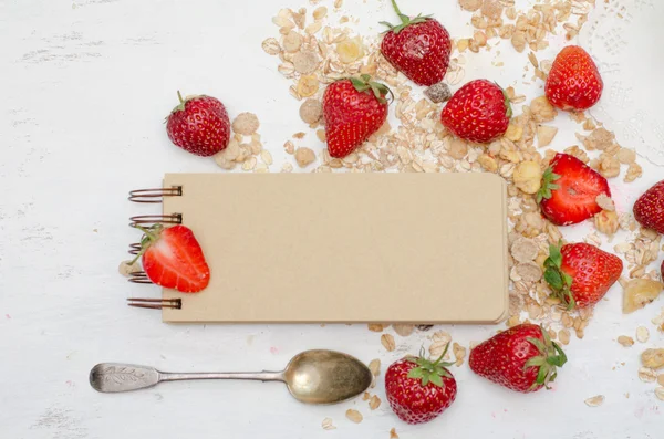 Blank notebook with craft brown pages, ripe strawberries and oat muesli for breakfast