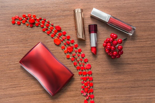 Red lipstick, lip gloss and powder box on a wooden background