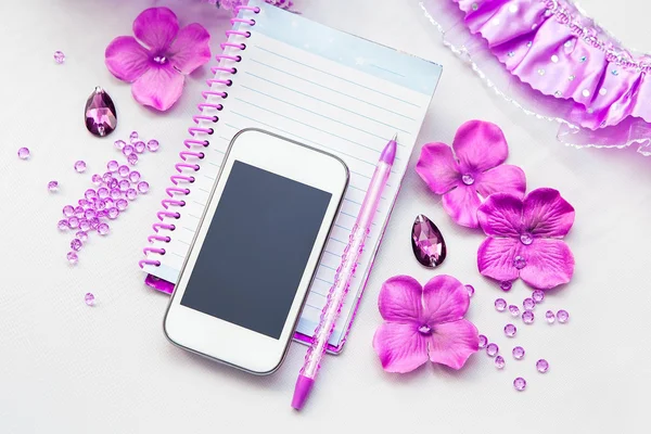 Office supplies business women. Phone, notebook and pen. Some office stuff on a white background. Accessories on the table. Purple pink color interior details.