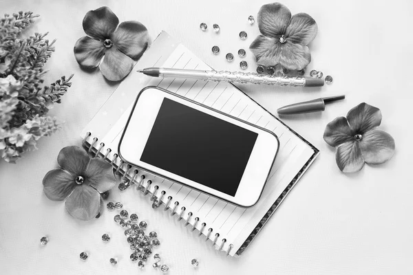 Phone, notebook and pen. Some office stuff on a white background. Accessories on a desk. Black and white color interior details.