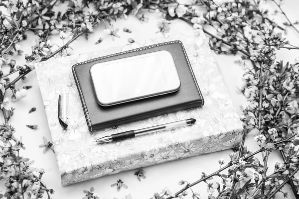 Office accessories with a beautiful blossom flower branches on a white background. Black and white style business photography.