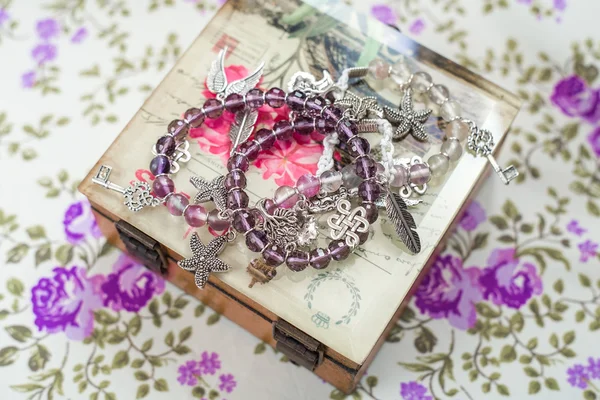 Silver bracelet with natural stones, shaped beads and crystals on a purple textile background