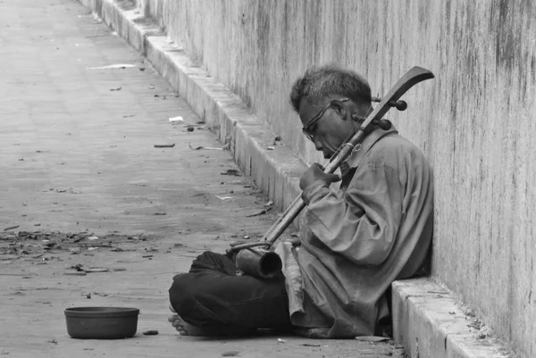 Elderly street musician sitting in street