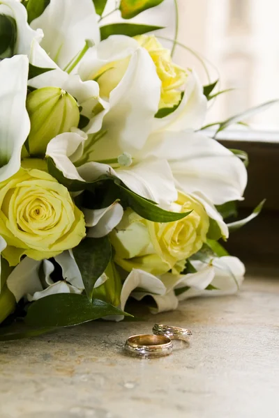 Wedding bouquet of lilies and roses, gold wedding rings