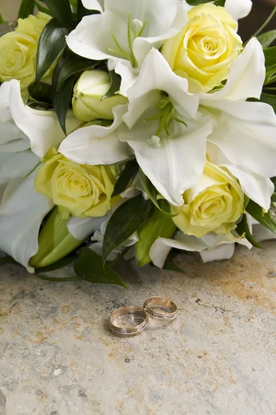 Wedding bouquet of lilies and roses, gold wedding rings