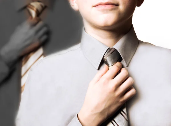 Boy straightens his tie hoping to become like father