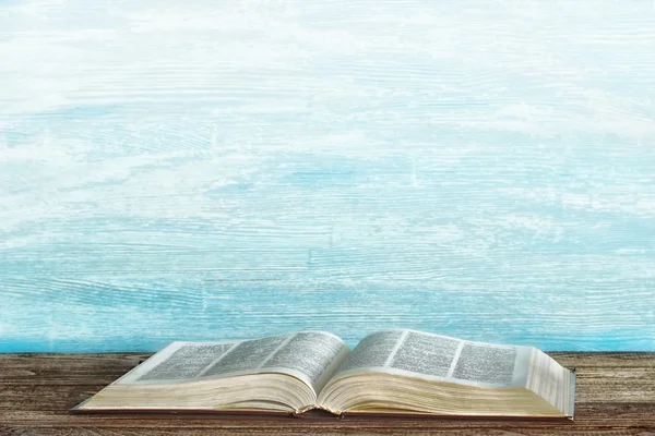 Open book on table on blue wooden background. Filtered. Style drawing on paper