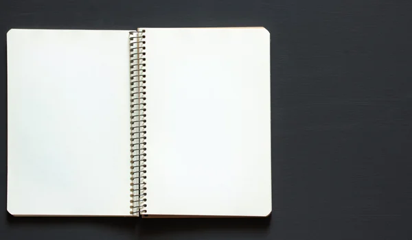 Single simple empty white notebook with a blank for drawing or writing is on a Desktop from black chalkboard. Top view. Mockup. Flat lay