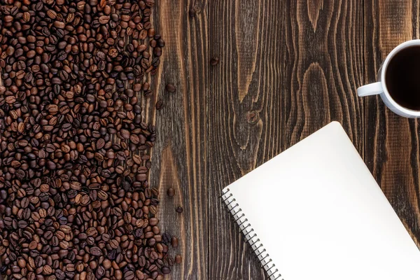 Cup of coffee single simple empty white notebook with a blank for drawing or writing and scattered roasted coffee