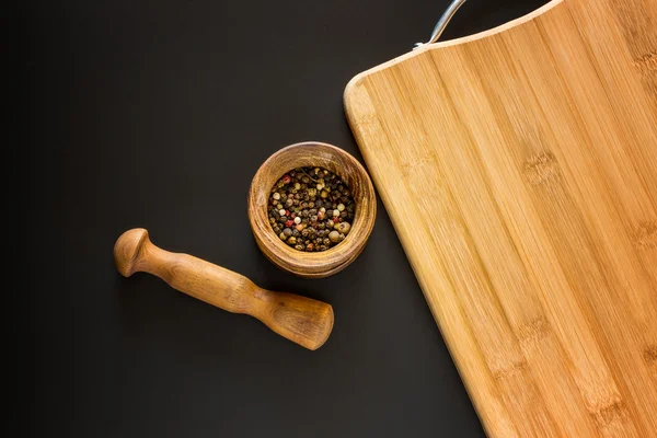 Food background. Wooden mortar with various spices and empty cutting board with blank space for mock up on black chalkboard. Topview. Mockup. Flatlay.