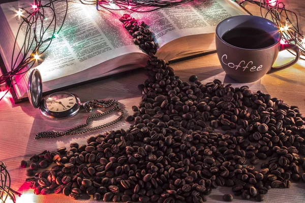 New year or chrismass background. Pocket watch, book and spilled coffee beans on a wooden desk surrounded by holiday garland