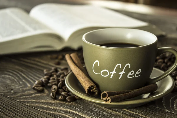A cup of coffee with beans on the background of a  book. Focus on  the cup