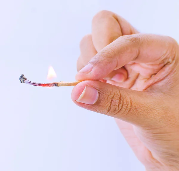 Hand holding a fired matchstick on a white background
