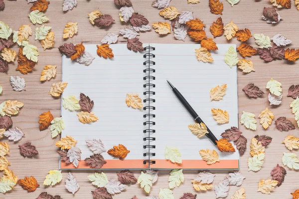 Spiral notebook with maple leaves on wood background