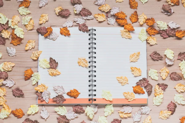 Spiral notebook with maple leaves on wood background