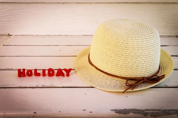 Straw hat with red clay text on wooden table