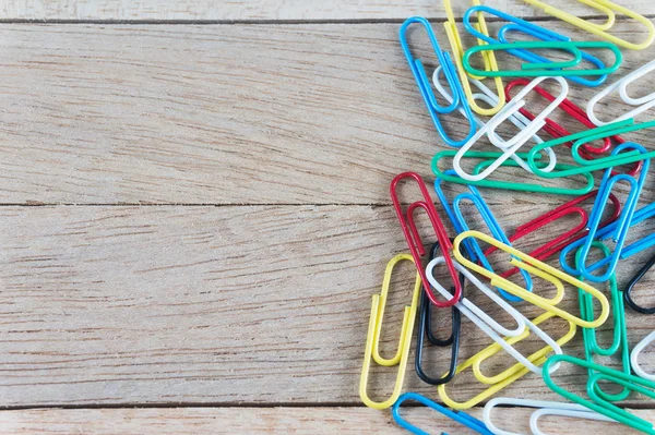 Colorful paper clips on wood background with copy space