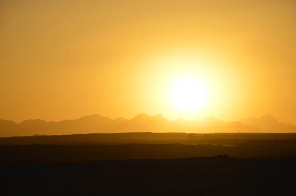 The sun sets behind the mountains