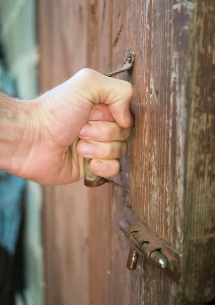 Hand on a handle old wooden door to open it.