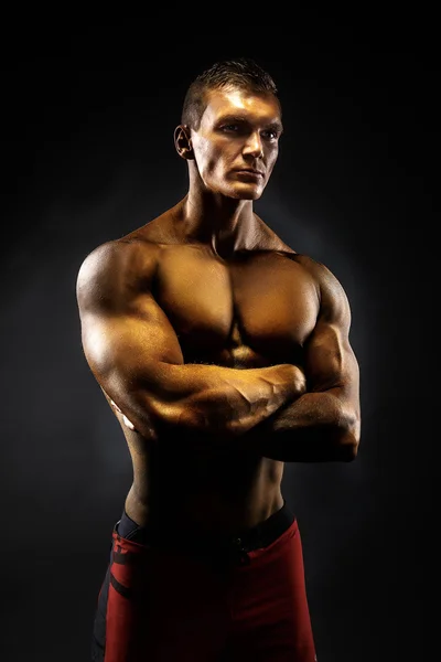Muscular man crossed his arms. black background