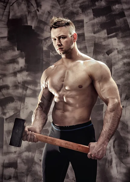 Athlete and hammer. guy with a nice muscle fitness, bodybuilder coach hold big metal hammer