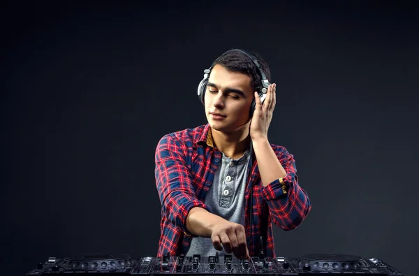 Young man play music on a djs mixer at studio