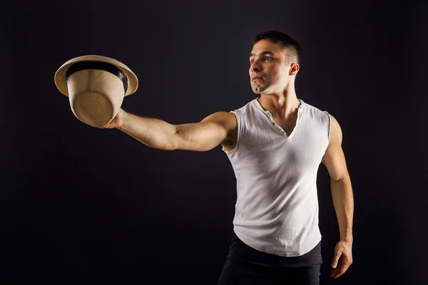 Man fashion model, stylish young man wearing fedora hat standing posing, over black background